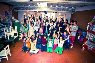 A whole class sits on a red tiled floor with their arms raised. Bogotá, Colombia, 2011.