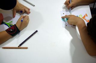 Hands from both sides drawing on one sheet on a white table. Barcelona, Spain, 2010.