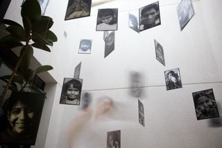 Black and white portraits hang at different heights in a white room. Barcelona, Spain, 2010.