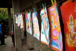 Colourful paintings pegged on a line along a stone veranda. Rishikesh, India, 2010.