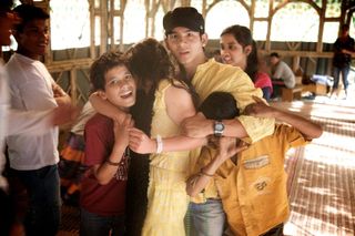 A tangle of young people hugging and laughing in a bamboo hall. Rishikesh, India, 2010.