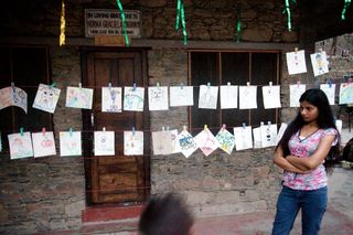 A woman looks at drawings pegged along a stone wall. Rishikesh, India, 2010.