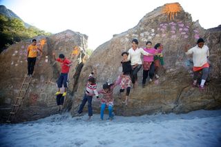 Children pose along the ledges of a big painted rock. The Ideal Place, 2011.
