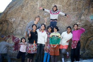 A group of children and young adults pose with arms wide in front of a chalk-covered rock. The Ideal Place, 2011.