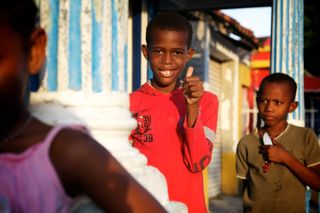 A smiling boy in a red shirt gives a thumbs up next to another boy. Barú, Colombia, 2011.
