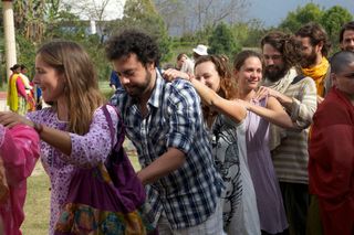 A line of adults walks in a row with hands on each other's shoulders. Rishikesh, India, 2012.