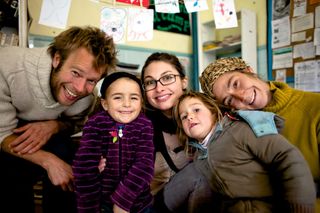 Three adults and two girls crowd together smiling at the camera. Spain, 2012.