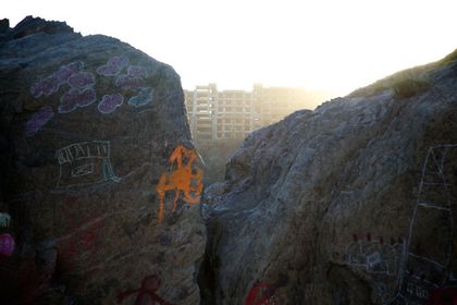 Two chalk-drawn boulders at dusk, with a building visible between them.
