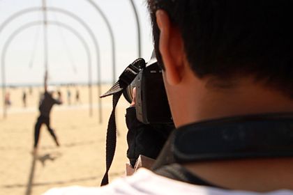 A view over a photographer's shoulder toward a beach.