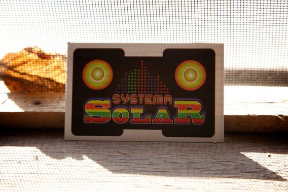 A painted box with the words Systema Solar, standing on a table outdoors.