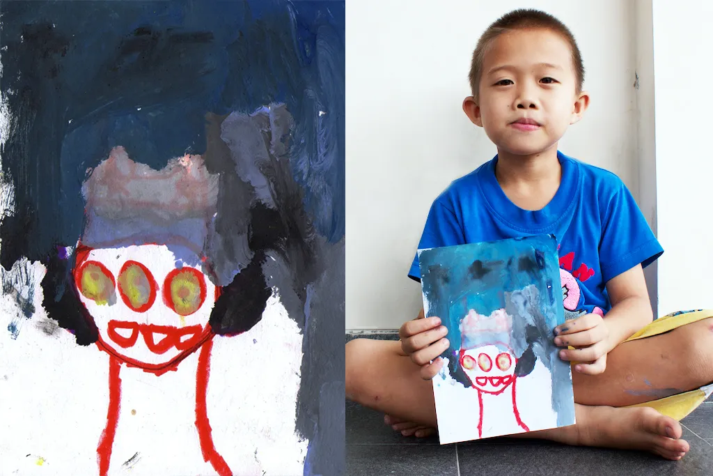 A painted alien with round eyes, beside a photograph of a child holding the painting.
