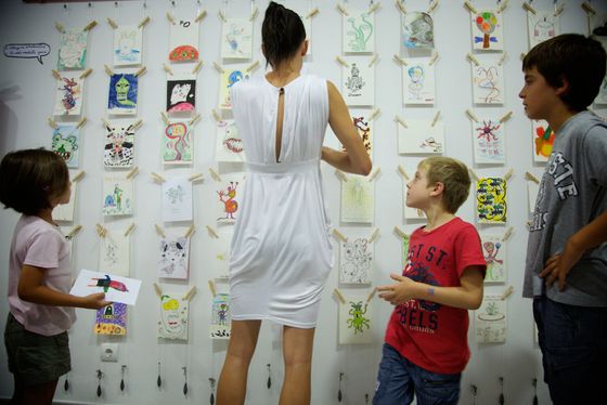 Visitors looking at a wall of alien drawings in an exhibition.