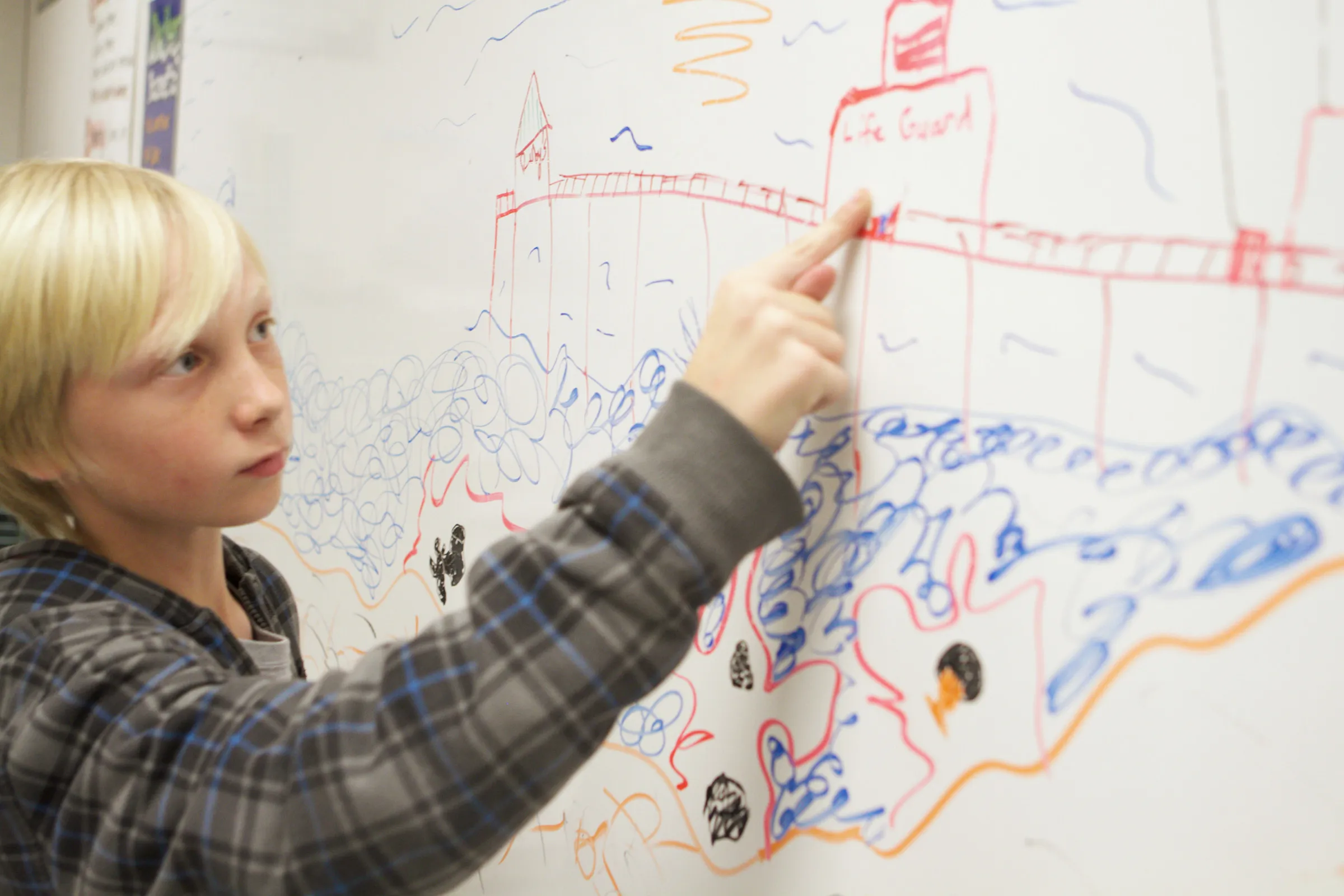 A child pointing at a large drawing of a landscape on a whiteboard.