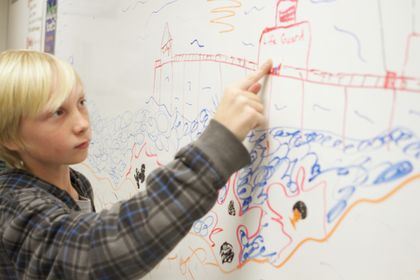 A child pointing at a large drawing of a landscape on a whiteboard.