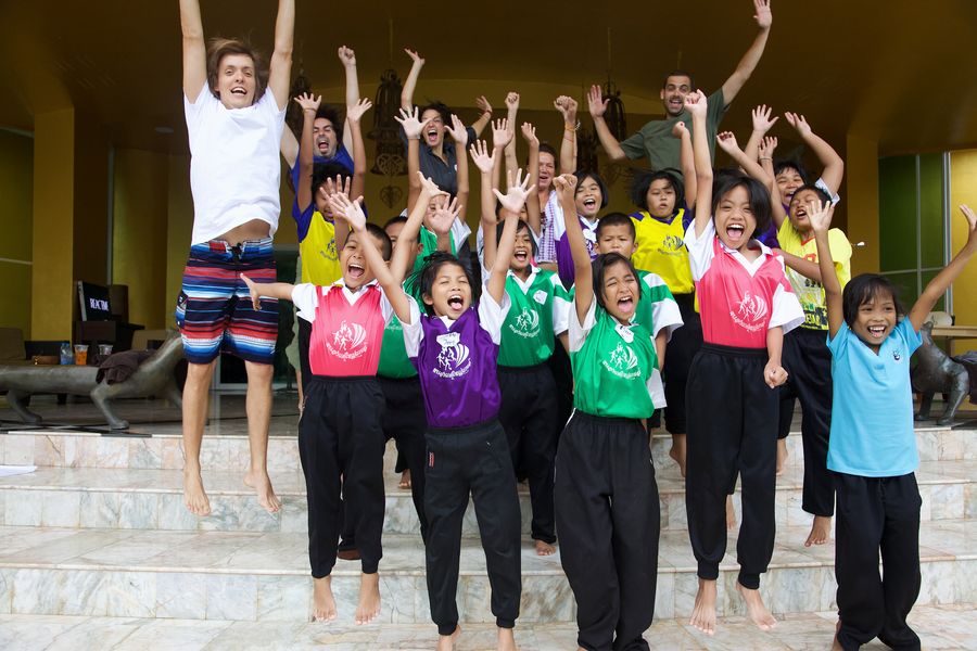 A group of children and adults jumping with arms raised on a staircase.