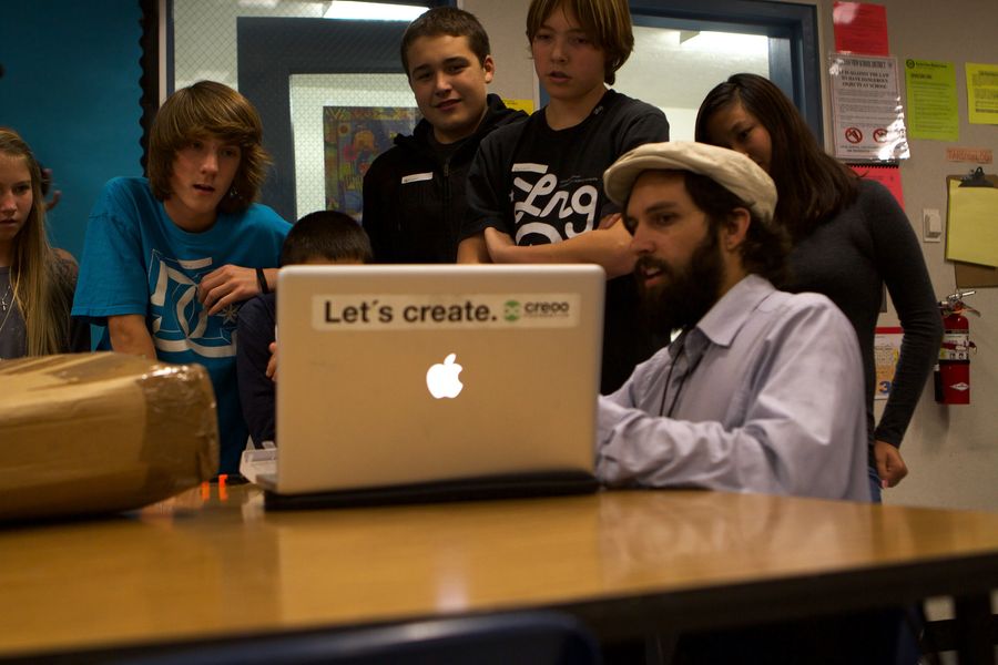 Teenagers and an adult gathered around a laptop.