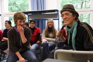 A laughing girl sits beside a man holding a microphone. Brandenburg, Germany, 2010.