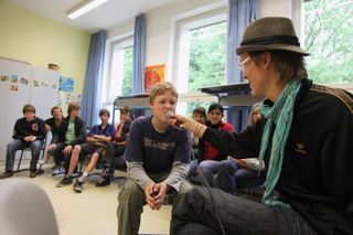 A boy leans toward the microphone a man holds out to him. Brandenburg, Germany, 2010.