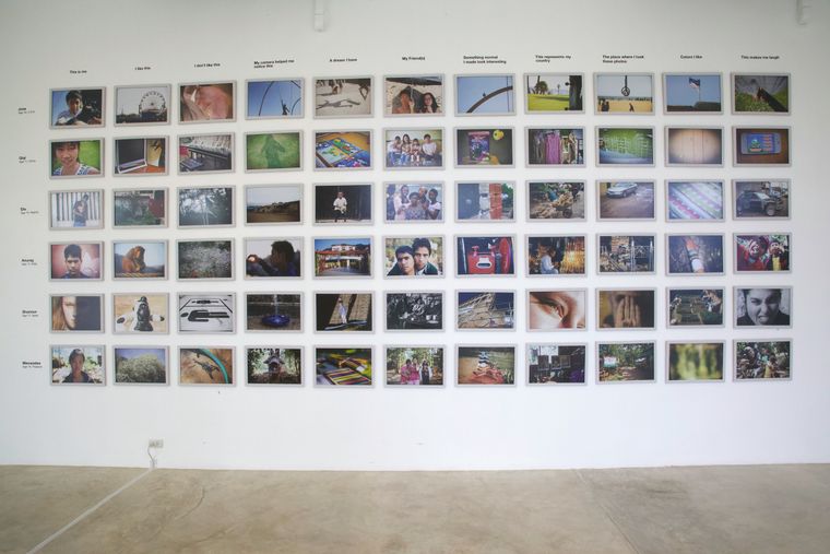 An exhibition wall of photographs in rows under printed task headings.