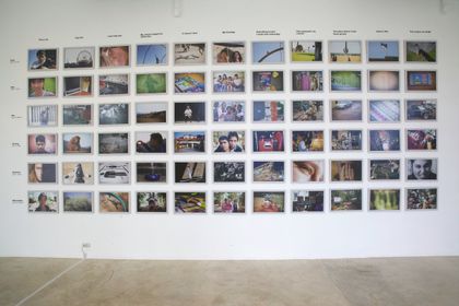 An exhibition wall of photographs in rows under printed task headings.