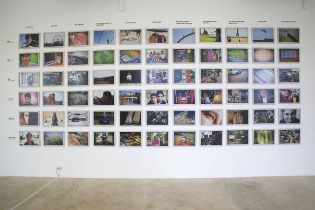 An exhibition wall of photographs in rows under printed task headings.
