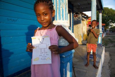 A child holding an alien drawing on a porch.